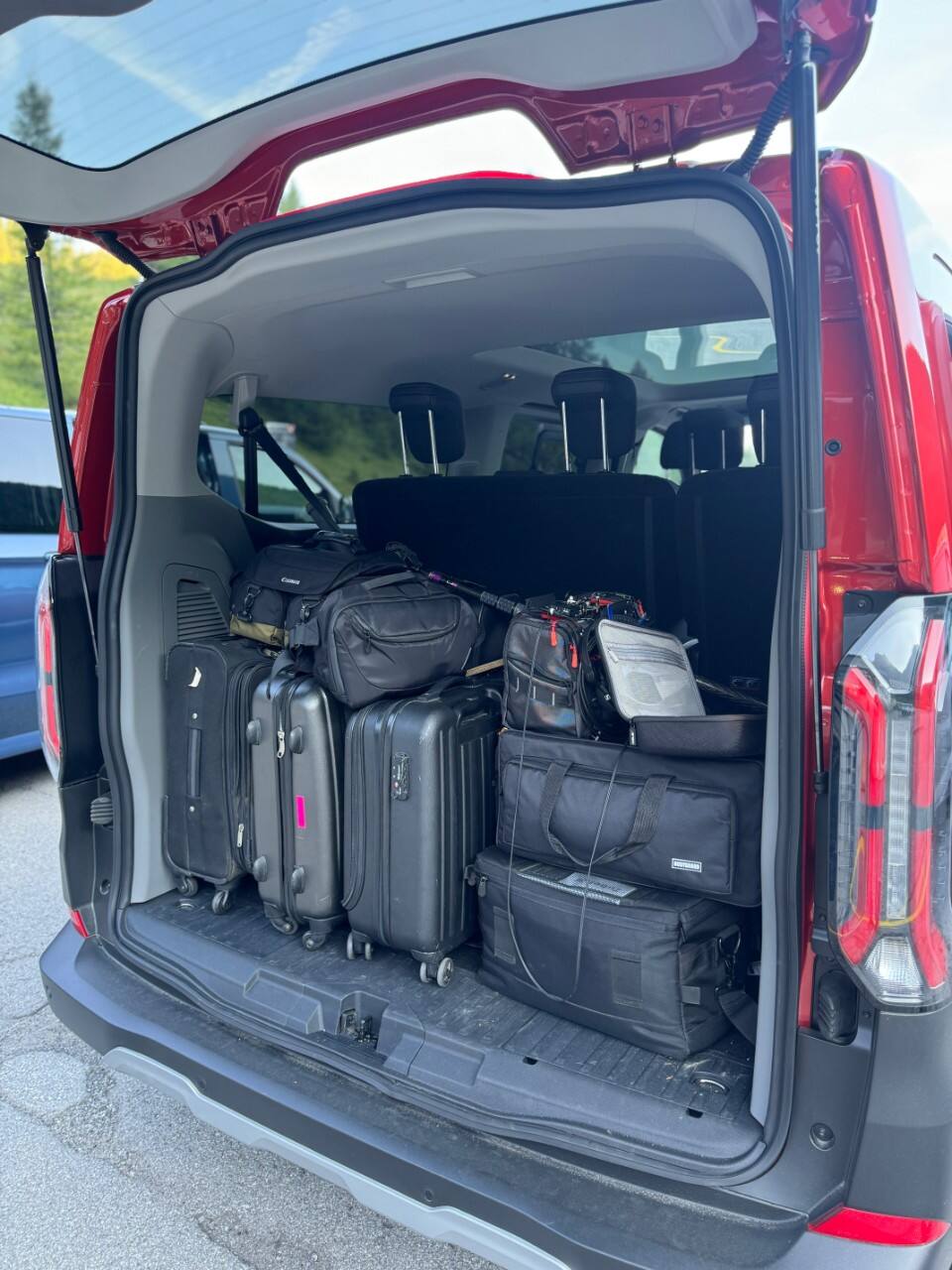 A red Tourneo Custom PHEV's packed trunk is shown from the back with the trunk open.